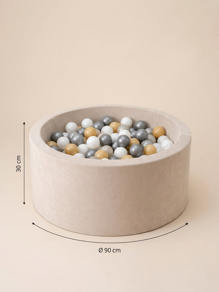 Rond beige ballenbad van 30 cm hoog en 90 cm doorsnee, gevuld met witte, grijze en goudkleurige ballen.