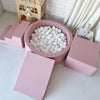 Roze ballenbad met witte ballen, omringd door een roze trapje, helling en blok, van bovenaf gezien.