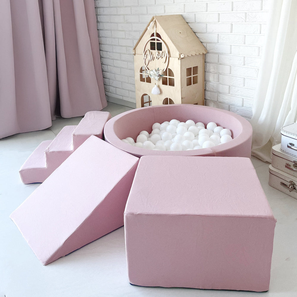Roze ballenbad met witte ballen, met een trapje links en een helling en kubusvormig blok op de voorgrond.