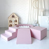 Roze speelset met een ballenbad met witte ballen, trapje links, helling in het midden en blok rechts.
