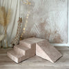 Donkerbeige velours speelparcours met trapje, blok en helling op een houten vloer, naast een pluchen giraf.