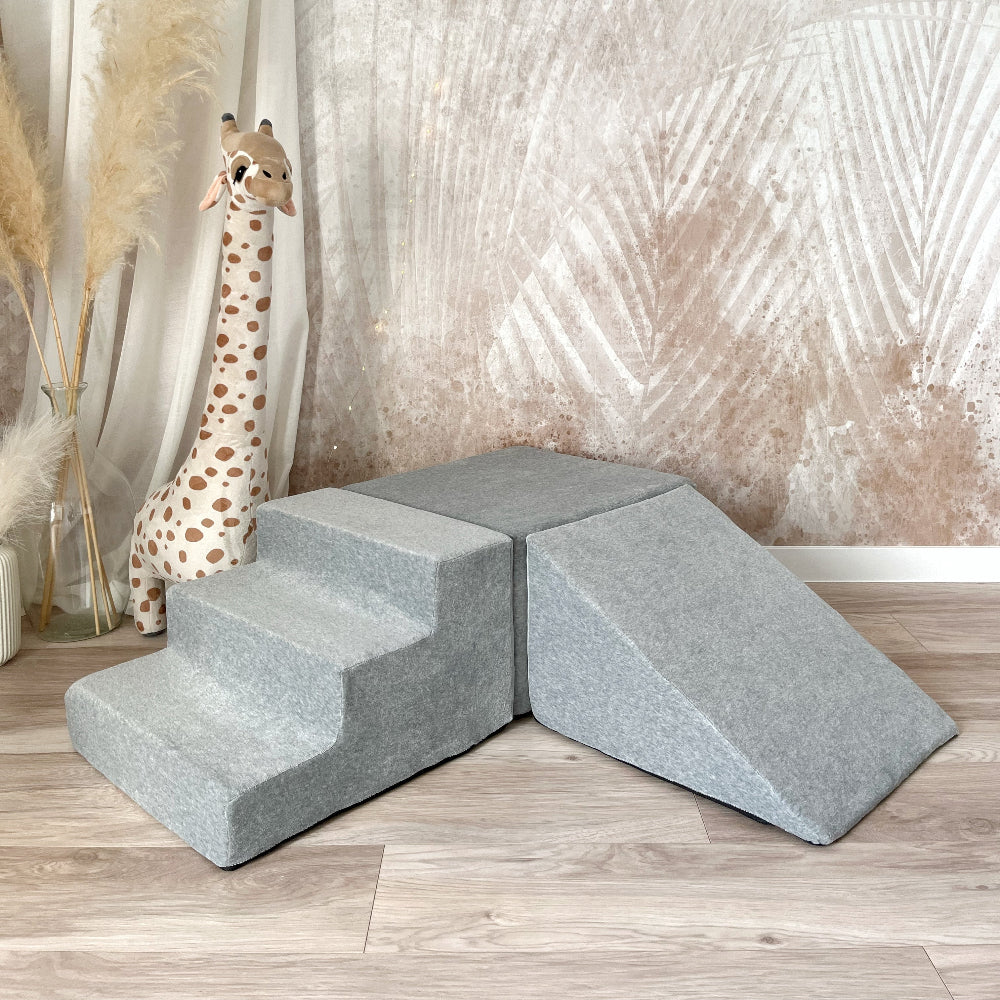 Grijs Soft Velvet speelparcours met trapje links, rechthoekig blok in het midden en helling rechts op een houten vloer.