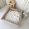 Vierkant beige ballenbad met witte, lichtgrijze en goudkleurige balletjes in een kinderkamer.