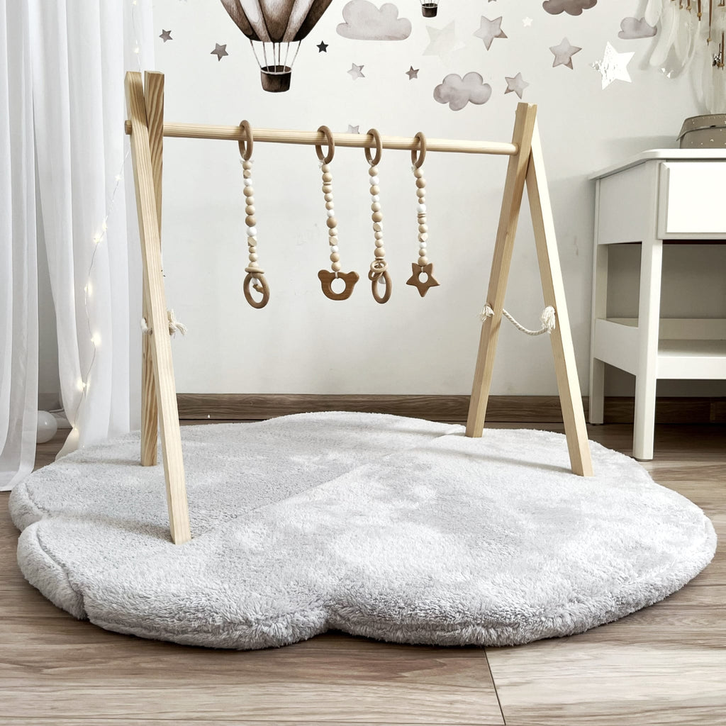 Grijze teddy speelmat Cloud in wolkvorm met een houten babygym erboven, van voren gezien.