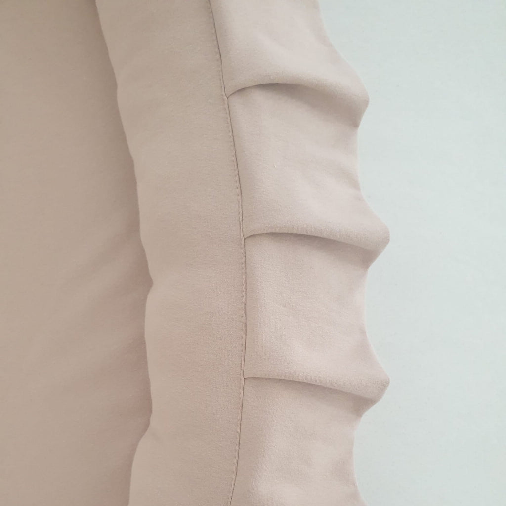 Detail van de beige katoenen hoes van het speelnest, met een gestikte naad en ruches langs de rand.