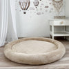 Beige teddy speelnest met opstaande rand op een houten vloer in een kinderkamer met luchtballonnen op de muur
