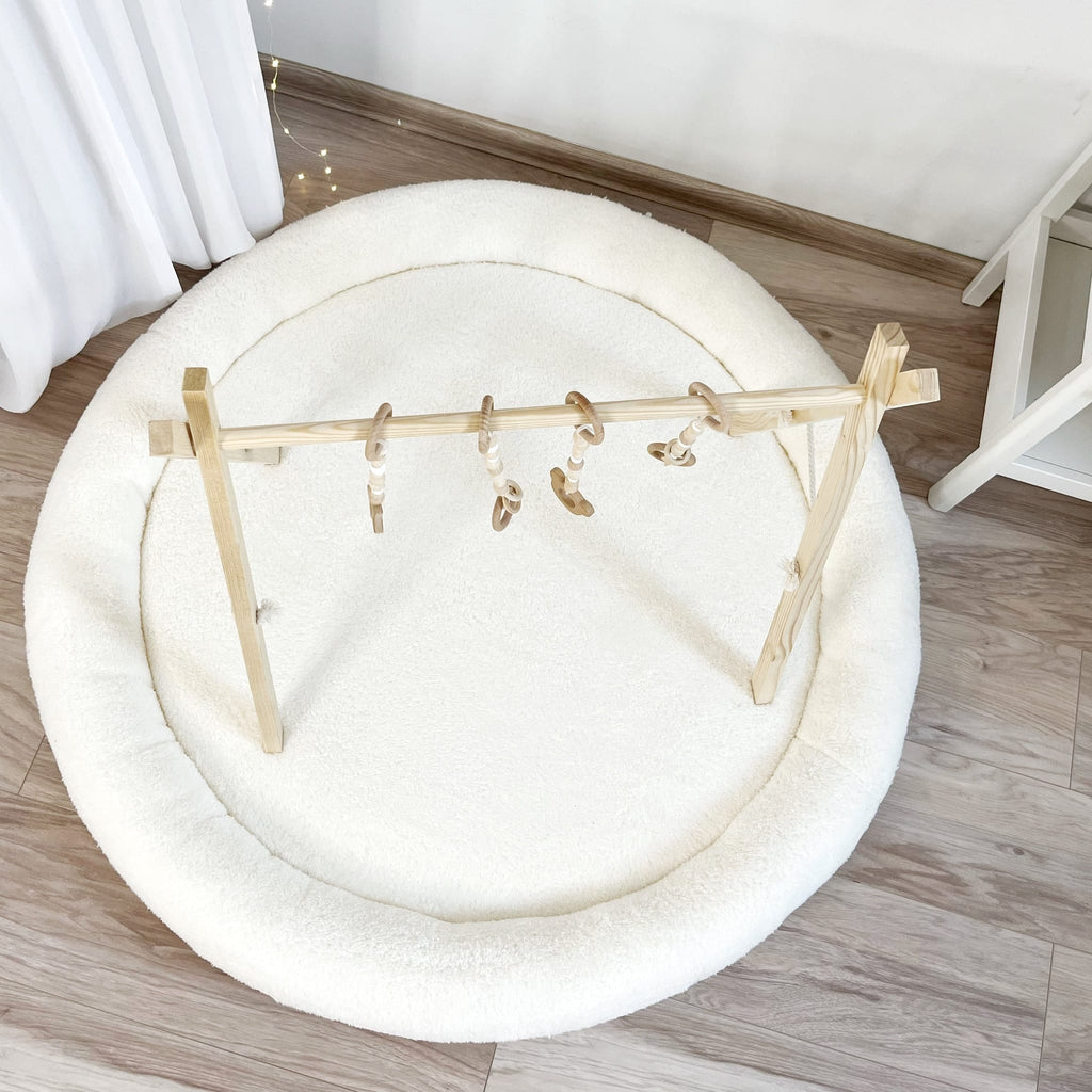 Wit teddy speelnest van bovenaf met een houten speelboog en hangend speelgoed